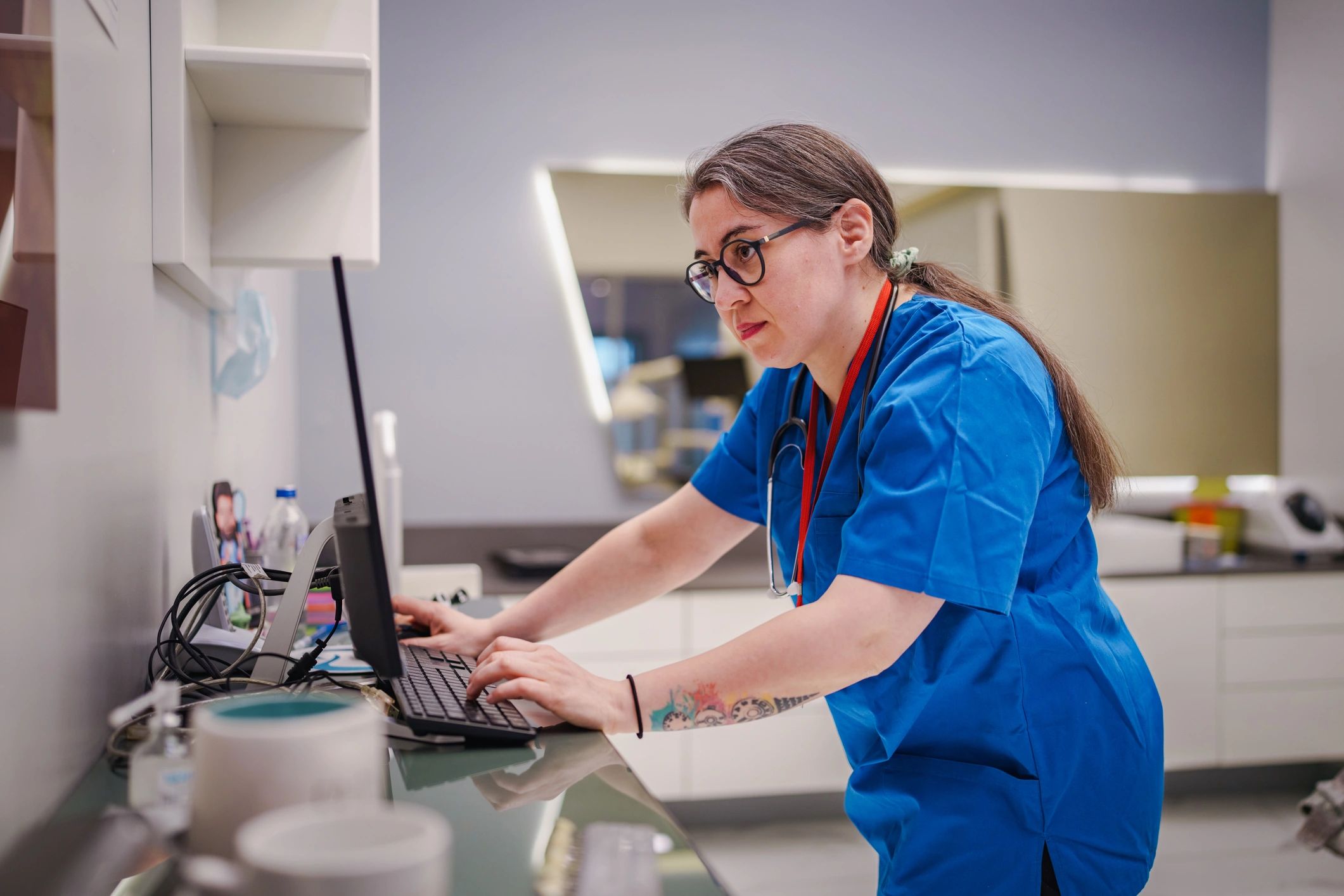 Clinic staff member at a desk using a computer and phone