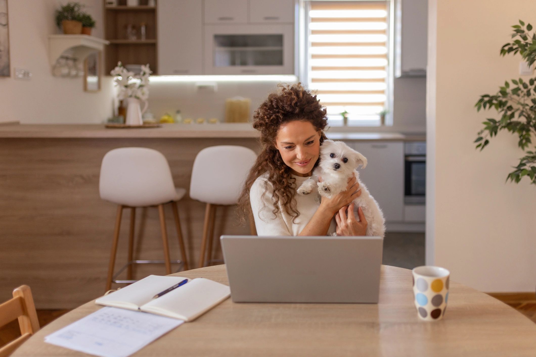 Pet owner using a laptop with a small dog nearby